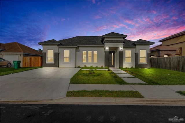 prairie-style home featuring a garage and a lawn