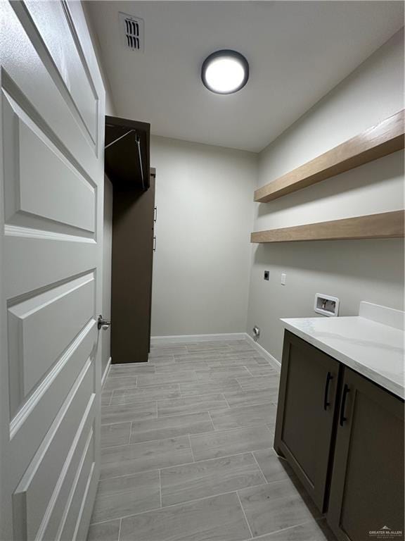 clothes washing area with hookup for an electric dryer, baseboards, visible vents, hookup for a washing machine, and cabinet space