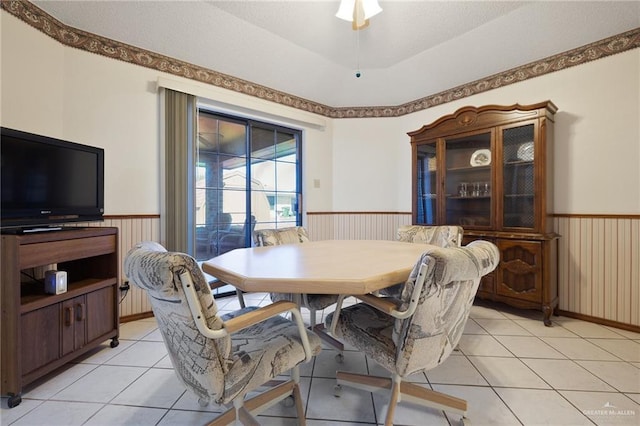 dining space with light tile patterned flooring and wainscoting