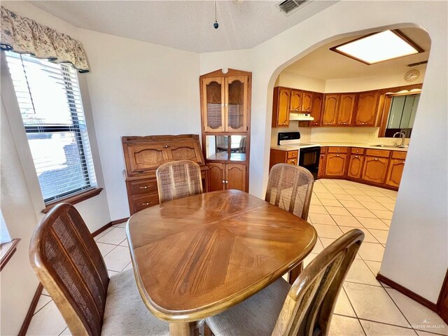 dining space featuring visible vents, baseboards, light tile patterned flooring, arched walkways, and a textured ceiling