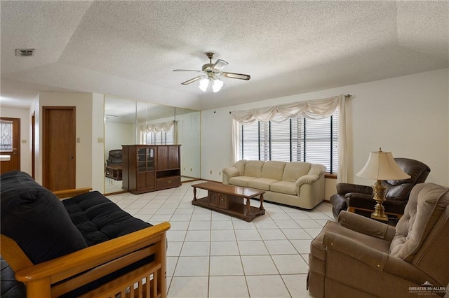 living area with light tile patterned floors, visible vents, a textured ceiling, and ceiling fan