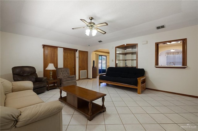 living area with arched walkways, visible vents, ceiling fan, and light tile patterned flooring