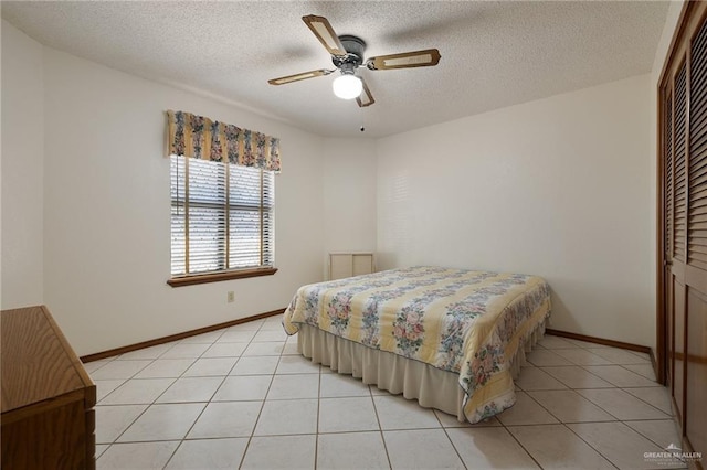 bedroom featuring light tile patterned floors, baseboards, a closet, and a textured ceiling