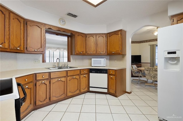 kitchen with a sink, visible vents, white appliances, and brown cabinets