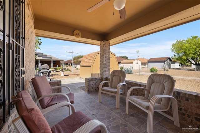 view of patio featuring an outdoor structure, fence, a shed, and ceiling fan