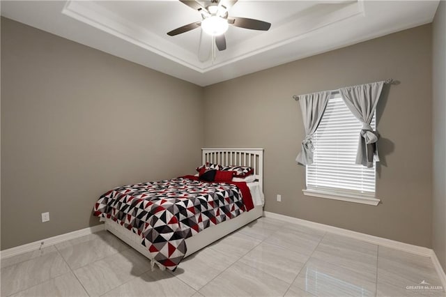 bedroom with a ceiling fan, a raised ceiling, and baseboards