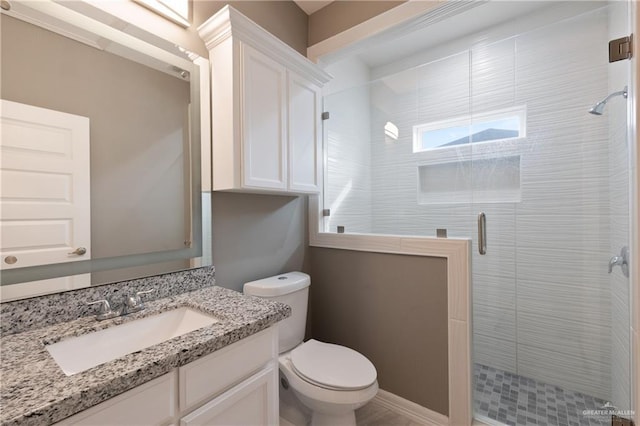 bathroom featuring a shower stall, toilet, and vanity