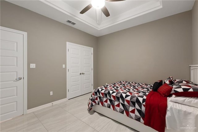 bedroom featuring visible vents, ceiling fan, baseboards, and a tray ceiling