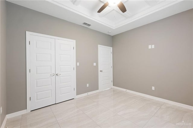 unfurnished bedroom featuring visible vents, a tray ceiling, a closet, baseboards, and ceiling fan