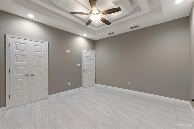 spare room with visible vents, a raised ceiling, baseboards, and ceiling fan