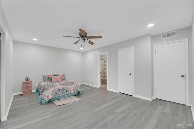 unfurnished bedroom with ceiling fan, ensuite bathroom, and light hardwood / wood-style flooring