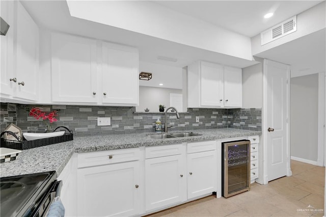 kitchen with decorative backsplash, white cabinetry, beverage cooler, and sink