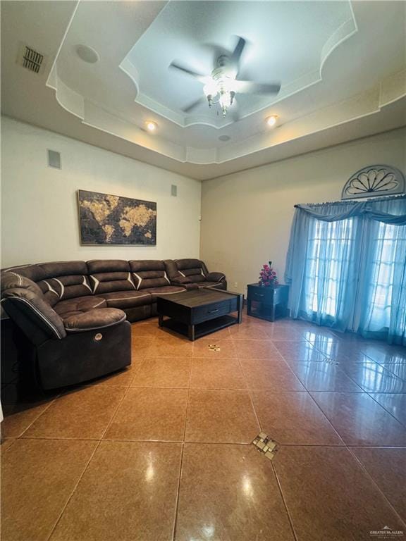 living room featuring a ceiling fan, tile patterned flooring, a raised ceiling, and visible vents