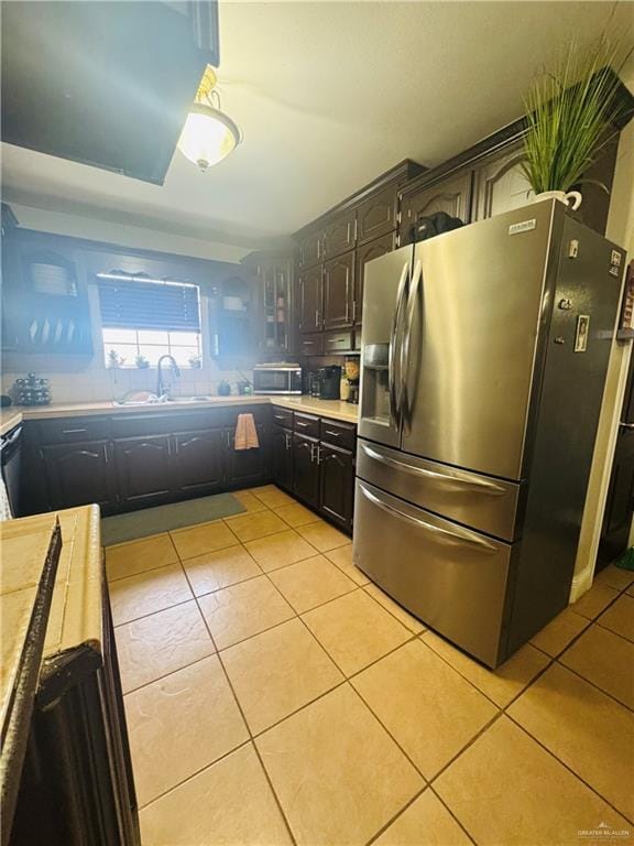 kitchen featuring light tile patterned floors, stainless steel appliances, a sink, and light countertops