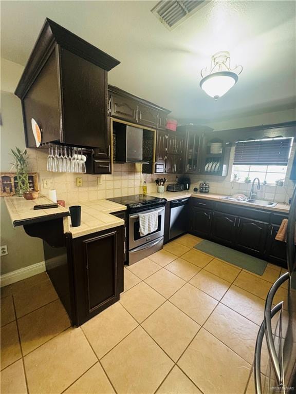 kitchen featuring a sink, light countertops, stainless steel electric range, decorative backsplash, and dishwasher