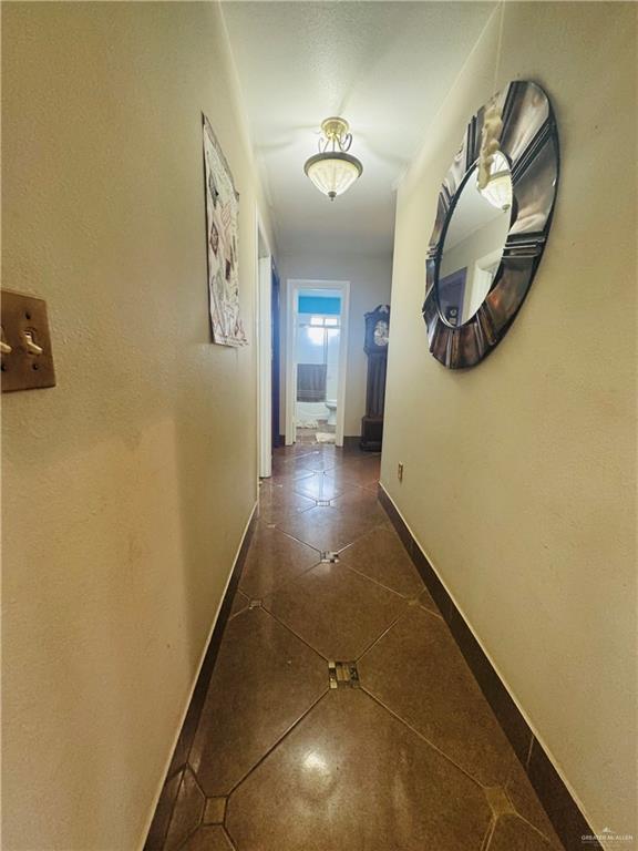 hall with dark tile patterned flooring and baseboards