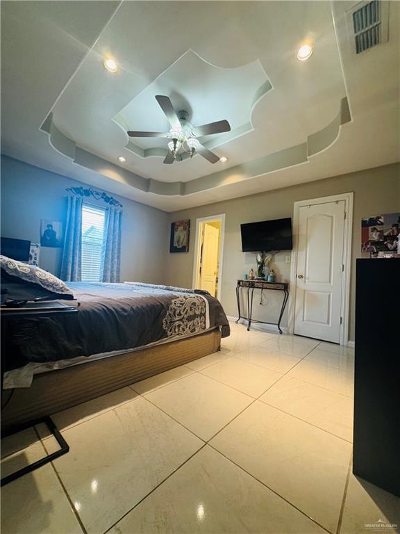 bedroom with light tile patterned floors, a tray ceiling, visible vents, and recessed lighting