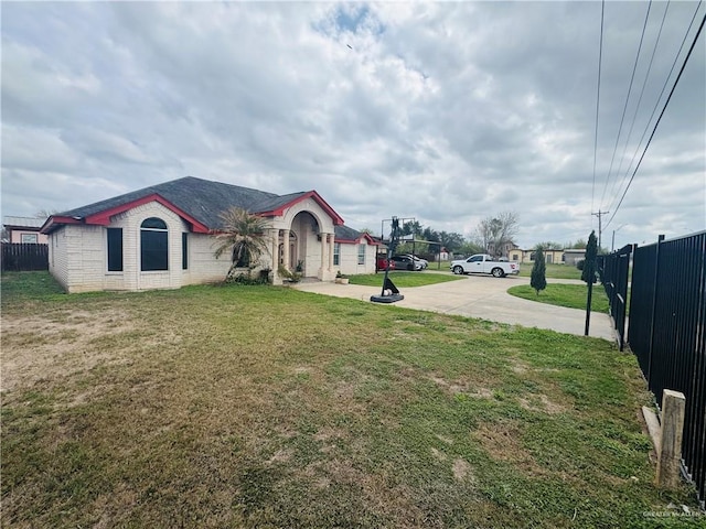 view of yard with concrete driveway and fence