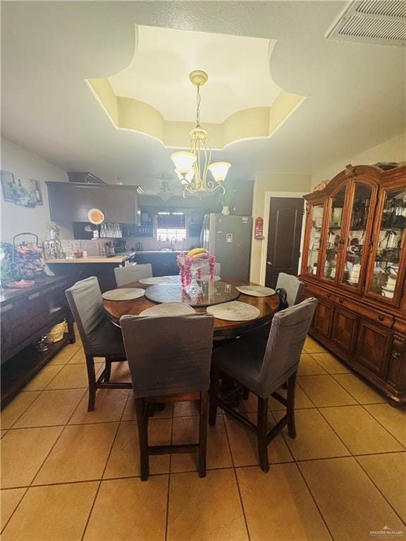 dining space featuring a chandelier, a tray ceiling, light tile patterned floors, and visible vents