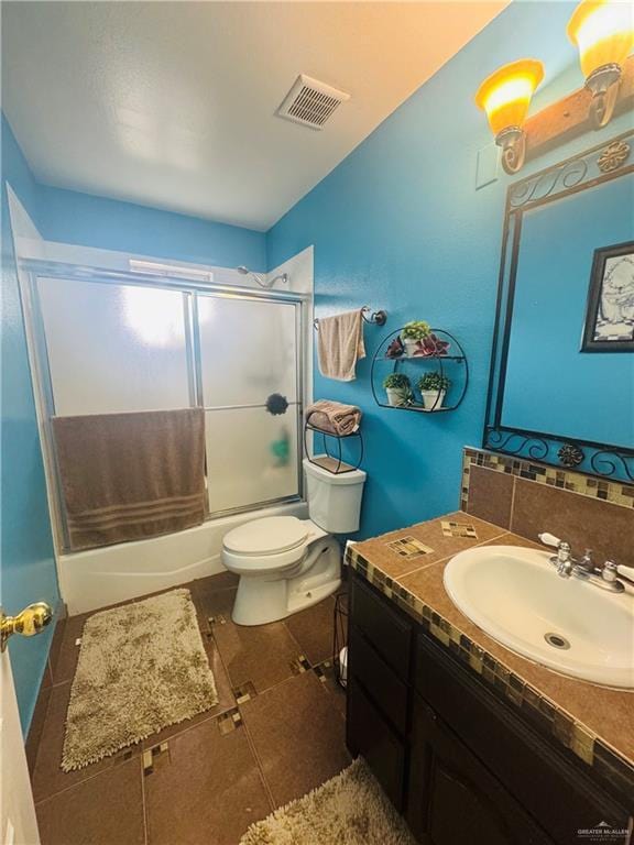 full bath with bath / shower combo with glass door, tasteful backsplash, visible vents, vanity, and tile patterned floors