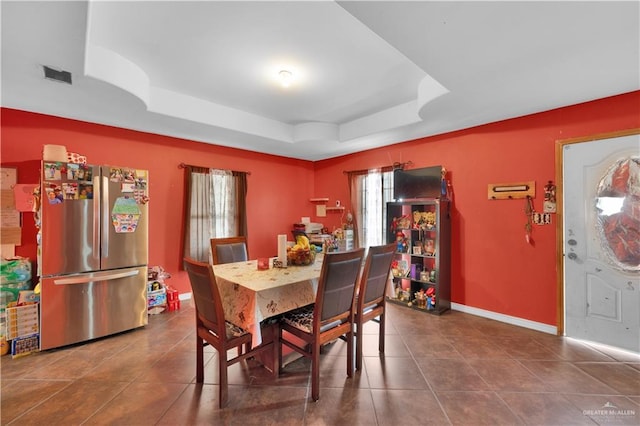 dining area with a tray ceiling, visible vents, baseboards, and tile patterned floors