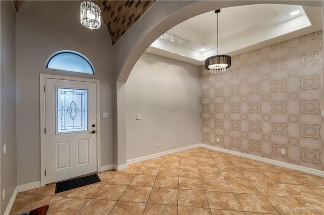 foyer featuring a towering ceiling, rail lighting, and light tile patterned flooring