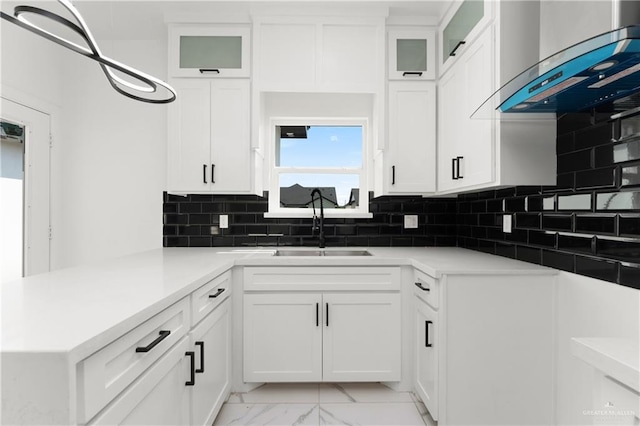 1922 Lime St, San Juan, TX 78589 - kitchen featuring wall chimney range hood, light marble finish floors, a peninsula, backsplash, and white cabinetry
