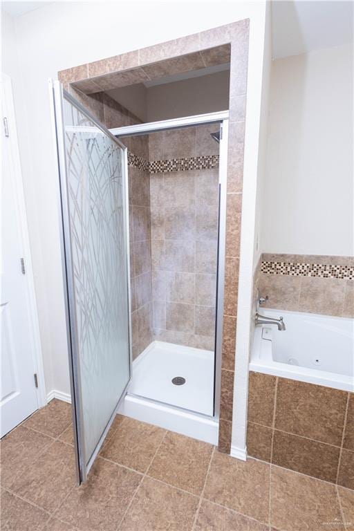 bathroom with a tub with jets, a stall shower, and tile patterned flooring