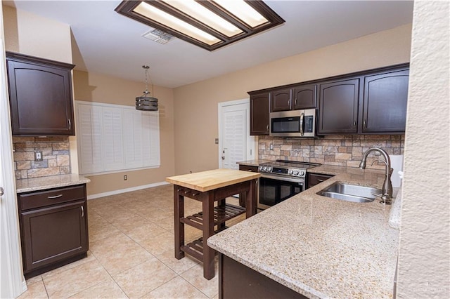 kitchen featuring visible vents, dark brown cabinets, appliances with stainless steel finishes, a sink, and backsplash