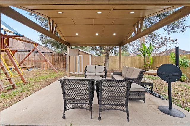 view of patio with a storage unit, a playground, and an outdoor living space