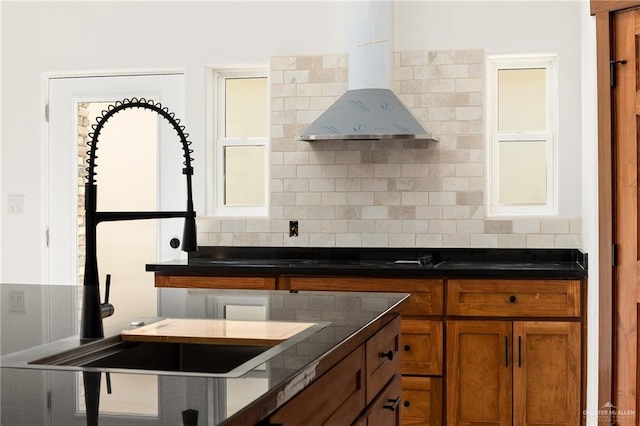 kitchen with tasteful backsplash, a wealth of natural light, sink, and wall chimney exhaust hood