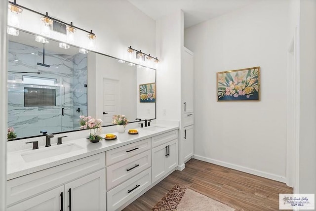 136 Finch Ln, Los Fresnos, TX 78566 - bathroom featuring a marble finish shower, wood finished floors, double vanity, and baseboards