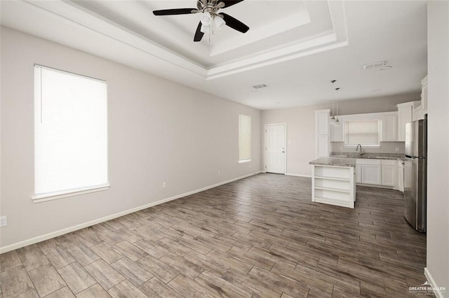 904 Kentucky St, Alton, TX 78573 - unfurnished living room with a ceiling fan, a tray ceiling, and dark wood-type flooring