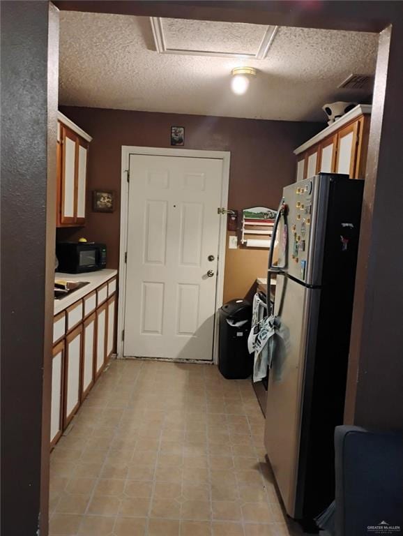 kitchen with stainless steel fridge and a textured ceiling