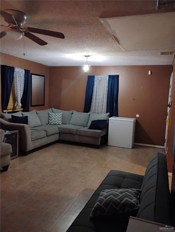 living room featuring ceiling fan and a textured ceiling