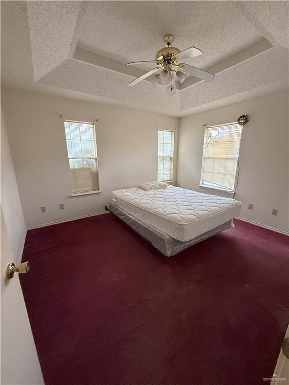 unfurnished bedroom featuring ceiling fan, a tray ceiling, and multiple windows