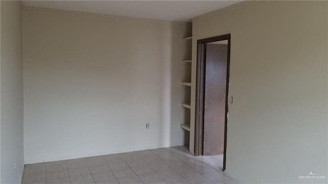 tiled spare room featuring crown molding