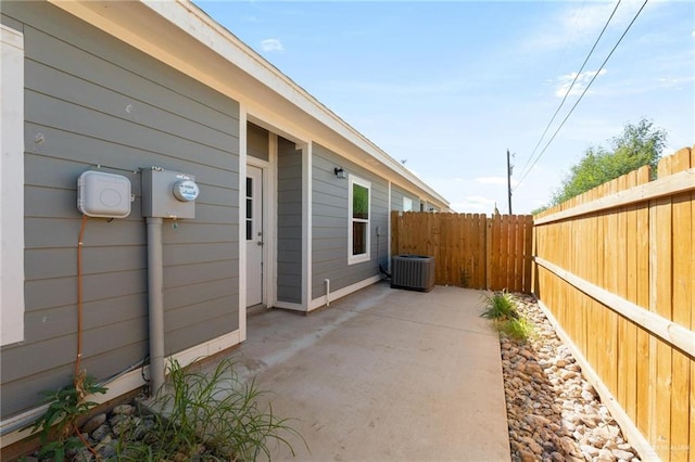 view of side of home with a patio, a fenced backyard, and central air condition unit