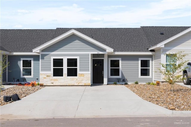 view of front of property featuring stone siding and roof with shingles