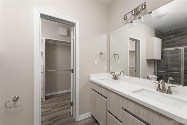 full bathroom featuring double vanity, wood finished floors, a sink, and toilet