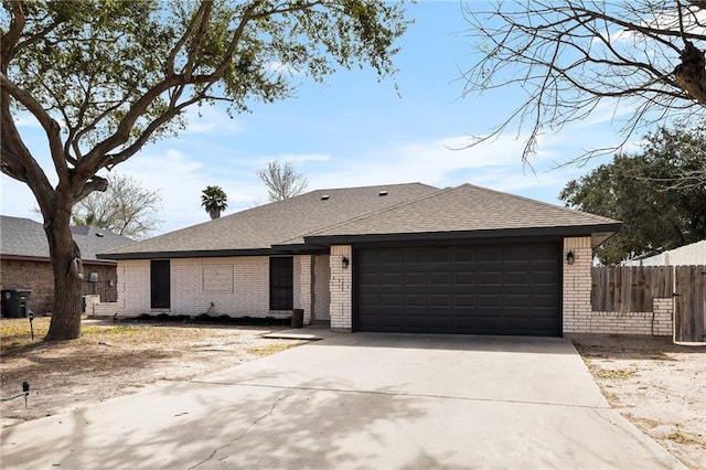 single story home with a garage, driveway, a shingled roof, fence, and brick siding