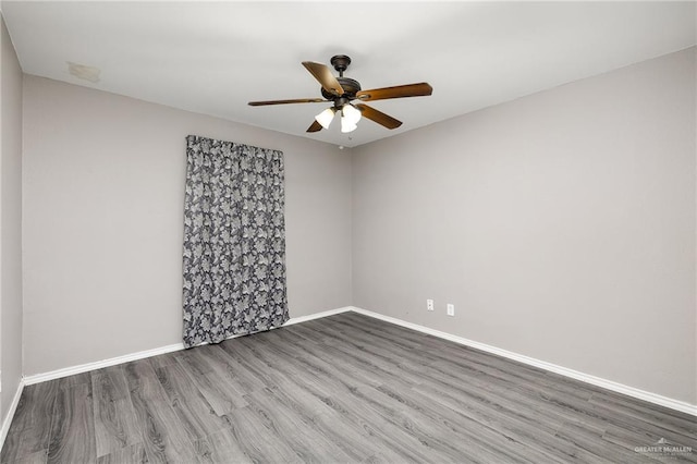 spare room with a ceiling fan, baseboards, and wood finished floors