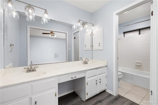 full bath with double vanity, a ceiling fan, toilet, and a sink