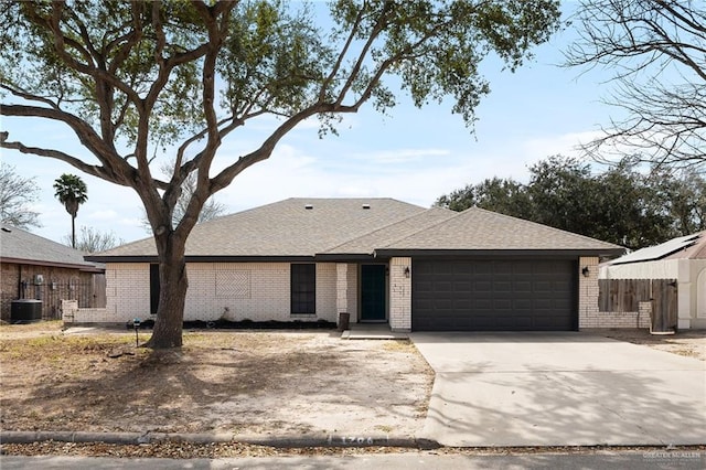 view of front facade with brick siding, a shingled roof, concrete driveway, an attached garage, and central AC unit