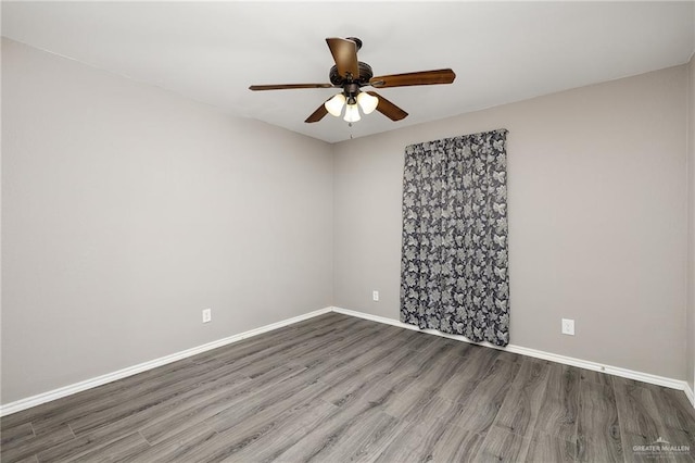 unfurnished room with wood finished floors, a ceiling fan, and baseboards