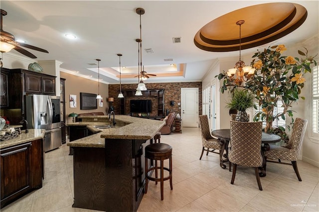 kitchen featuring sink, stainless steel fridge with ice dispenser, a tray ceiling, a breakfast bar, and ceiling fan with notable chandelier