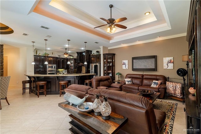 living room featuring a raised ceiling, ceiling fan, and ornamental molding