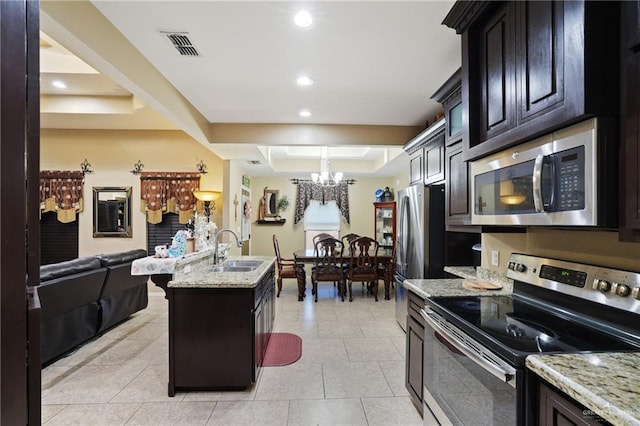 3008 Brush Dr, Weslaco, TX 78599 - kitchen featuring stainless steel appliances, a chandelier, a sink, light stone countertops, and a tray ceiling