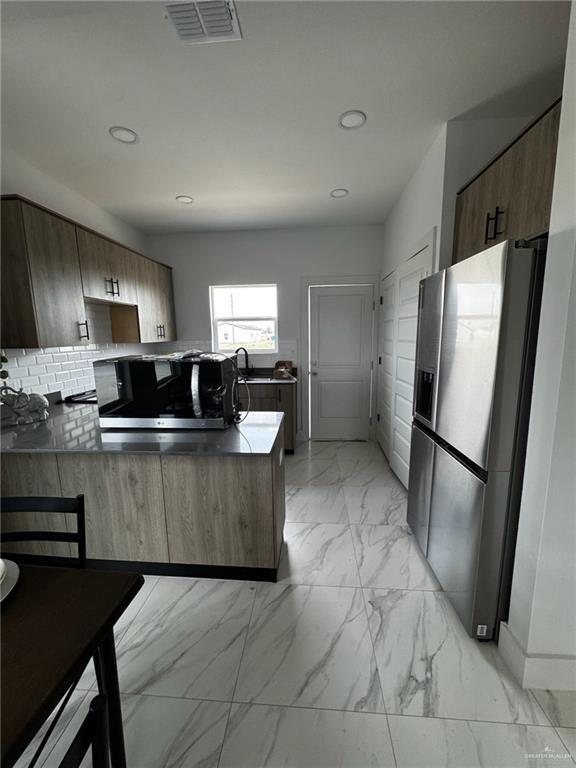 2809 Alpha Rd, Weslaco, TX 78596 - kitchen featuring stainless steel appliances, decorative backsplash, marble finish floor, visible vents, and a peninsula