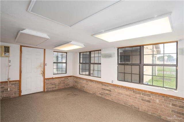 carpeted spare room featuring brick wall